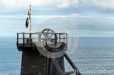 The pithead of a Cornish tin mine showing the main lifting pulley, with a Cornish nationalist Kernow flag Stock Photo