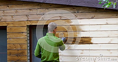 Pittore con la facciata della casa della pittura del pennello con colore protettivo di legno Pittore con la facciata della casa della pittura del pennello con colore protettivo di legno