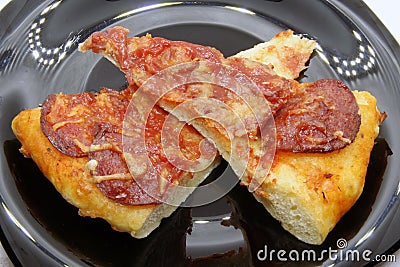 Pizza cuts on a black plate. Pizza slice on a black plate. Stock Photo