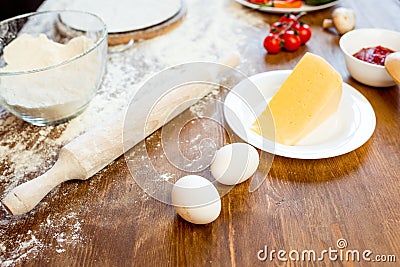 Pizza ingredients, eggs and cheese on wooden tabletop Stock Photo
