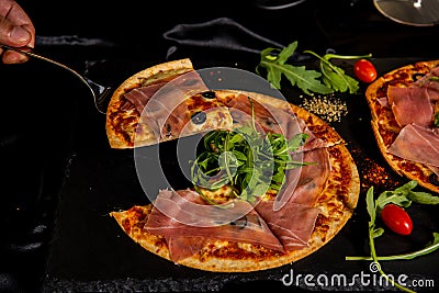 Pizza Jamon IbÃ©rico and Rocket salad served on slate table Stock Photo