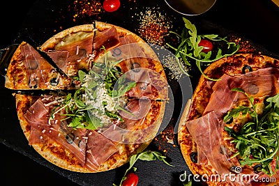 Pizza Jamon IbÃ©rico and Rocket salad served on slate table Stock Photo