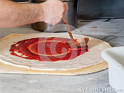 Pizza Maker puts on the sauce Stock Photo