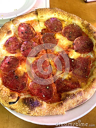 pizza meat circle slice tasty hot pepperoni covered tomatoes with prosciutto and spices on plate Stock Photo