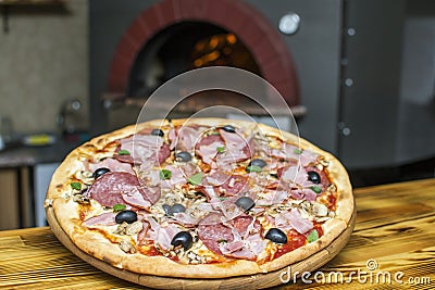 Pizza near the stone stove with fire. Background of a traditional pizzeria restaurant with a fire place Stock Photo