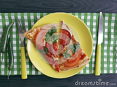 pizza piece with sausage fork knife on a black woodenl unch Stock Photo