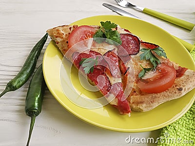 Pizza piece portion sausage fork pepper knife towel tomato on white wooden Stock Photo