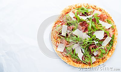 Pizza with prosciutto (parma ham), arugula (salad rocket) and parmesan on white background top view Stock Photo