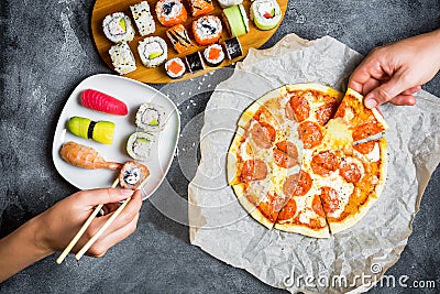 Pizza with salami, set of sushi rolls and hands take food. Food background. Flat lay, top view. Stock Photo