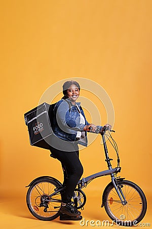 Pizzeria worker carrying food delivery thermal backpack standing riding bike Stock Photo