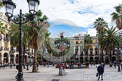 Placa Reial, shaded by palms and cooled by a fountain. Colorful lamp posts known as GaudÃ¬ first opera in the center. Barcelona Editorial Stock Photo