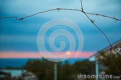 Place of detention. Prison. Jail. Sunset view from protected location. Barbed wire. Stop sign. Blue sky. Dangerous area Stock Photo