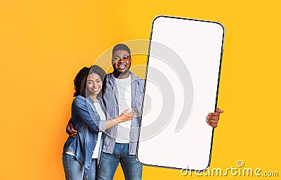 Excited black couple showing white empty smartphone screen Stock Photo