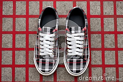 plaid patterned sneakers standing on a concrete surface Stock Photo