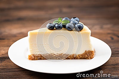 Plain New York Cheesecake Slice Topped With Blueberries And Mint Leaf Stock Photo