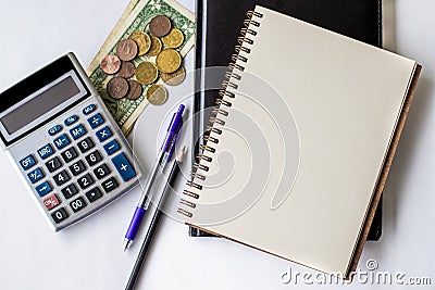 Plain Spiral Notebook With Pen Beside Calculator And Coins On Table. Simple Notepad And Ballpen Alongside Calculation Stock Photo