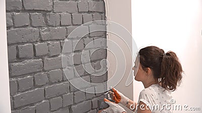 Plan rapproché d'une femme peignant un mur de briques dans le gris utilisant un pinceau clips vidéos Plan rapproché d'une femme peignant un mur de briques dans le gris utilisant un pinceau clips vidéos