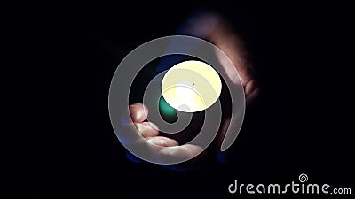 Plan rapproché d'une petite bougie aromatique dans les paumes d'un homme sur le noir 4 K Tir au ralenti Plan rapproché d'une petite bougie aromatique dans les paumes d'un homme sur le noir 4 K Tir au ralenti