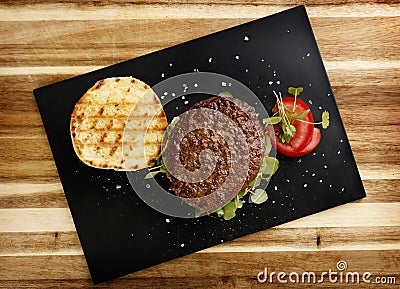 Plan view of a succulent and juicy rare beef burger, with tomato and watercress garnish, in a bread bun Stock Photo