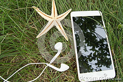 Plan your beach holidays and travel on the grass with the phone, headphones, starfish Stock Photo