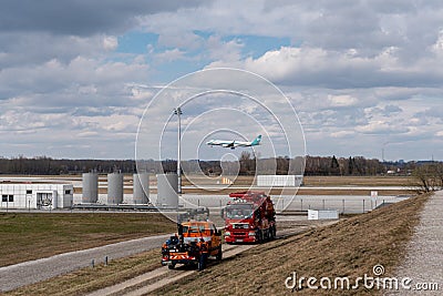 Plane from Air Dolomiti airline landing on the airport of Munich with a cloudy sky and two cleaning Editorial Stock Photo
