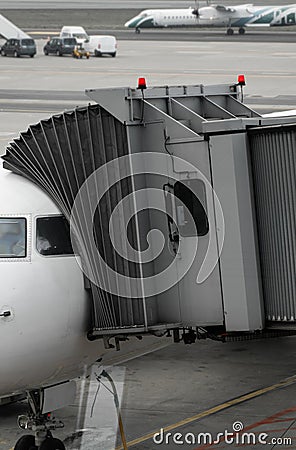 Plane on airport connected to gate sleeve. Aircraft and sleeve. Gate at the airport for passengers to plane boarding. Stock Photo