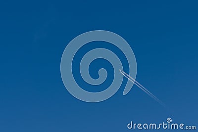 plane with contrails in a blue sky Stock Photo