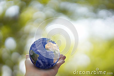 Plane Earth globe ball in human hand on green sunny background. Saving environment, save clean planet, ecology concept. Stock Photo