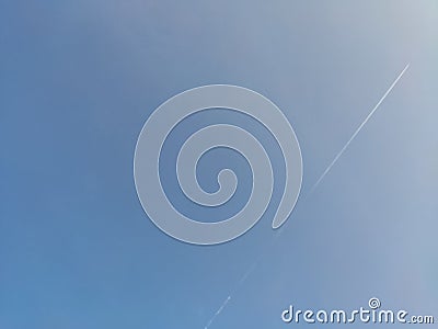 The plane flew high in the blue sky on a clear day and left a beautiful trail of smoke Stock Photo