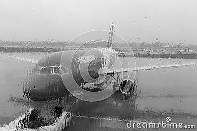 Plane before flight through blurred window with raindrops. Plane black and white. Avaition concept. Stock Photo