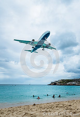 Plane landing flying over famous Maho Beach Editorial Stock Photo