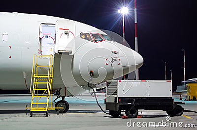 Plane parked at the airport at night, view nose cockpit. Stock Photo