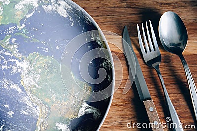 The planet Earth plate with a fork and knife on a wooden background. World hunger concept. Feed the world Stock Photo