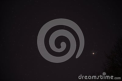 The planet Venus in the starry night sky in conjunction with the Pleiades Constellation Stock Photo