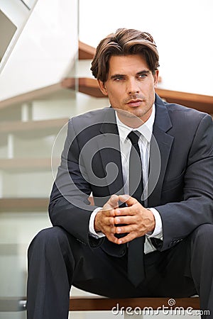 Planning his next business move. A handsome young businessman sitting on the stairs deep in thought. Stock Photo