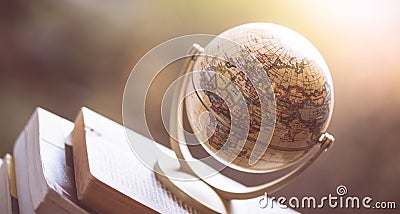 Planning the next journey: Miniature globe on a stack of books Stock Photo