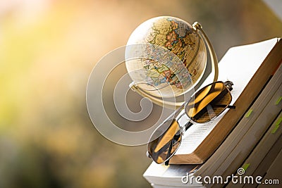 Planning the next journey: Miniature globe and sunglasses on a stack of books Stock Photo