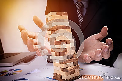 Planning, risk and strategy in business concept, businessman gambling placing wooden block on a tower Stock Photo