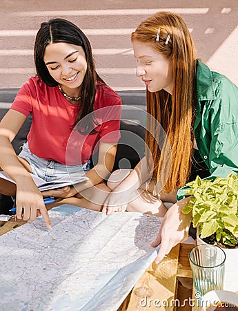 Planning trip. Young friends teen girls summer vacation with map Stock Photo