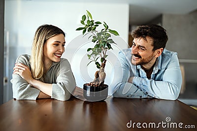 Plant care. Nature protection concept. Smiling environmentally friendly couple with houseplants. Stock Photo