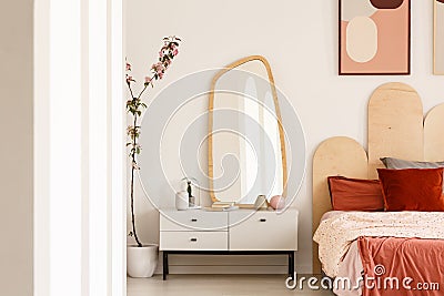 Plant next to white dressing table with mirror in red bedroom in Stock Photo