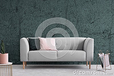 Grey couch with cushions in dark apartment interior with textured wall. Real photo Stock Photo