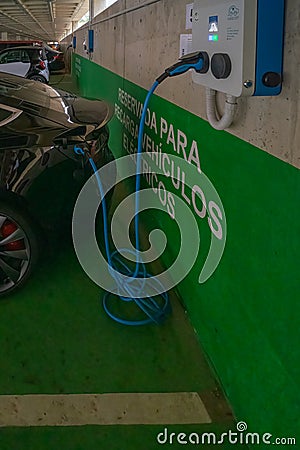 Charging a modern electric car in a public parking lot, they are the future with their smart technology. Tesla Editorial Stock Photo