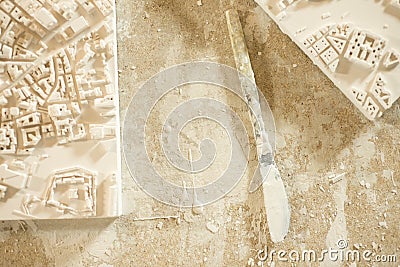 Plaster-Coated Knife Between 3D City Map Plaster Models Stock Photo