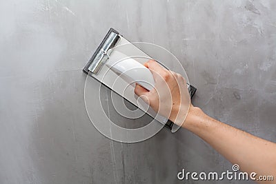 Plasterer erases irregularities on the wall with trowel. Stock Photo