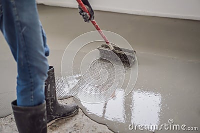 plasterer during floor covering works with self-levelling cement mortar, uses a needle roller Stock Photo