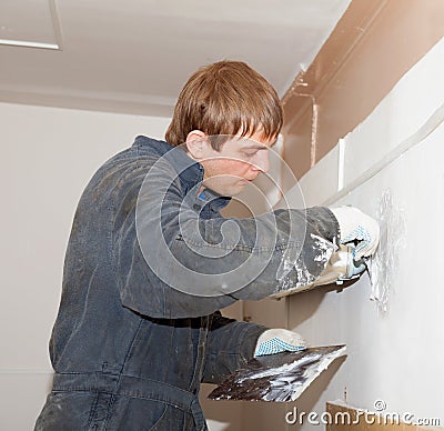 Plasterer at indoor renovation decoration with putty knife Stock Photo