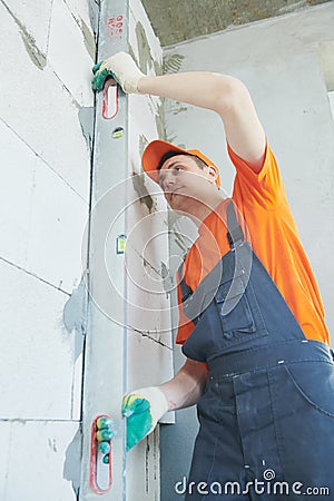 Plasterer levelling screed on wall for plastering Stock Photo