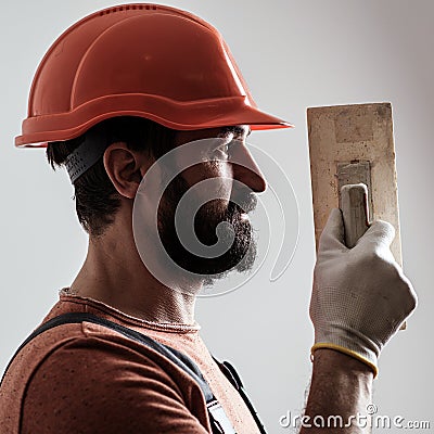 Plasterer renovating wall. Profile of bearded builder. Worker with wall plastering tools. Renovating house concept Stock Photo