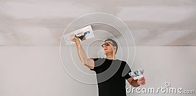 Plasterer smoothing plaster ceiling with the trowel Stock Photo